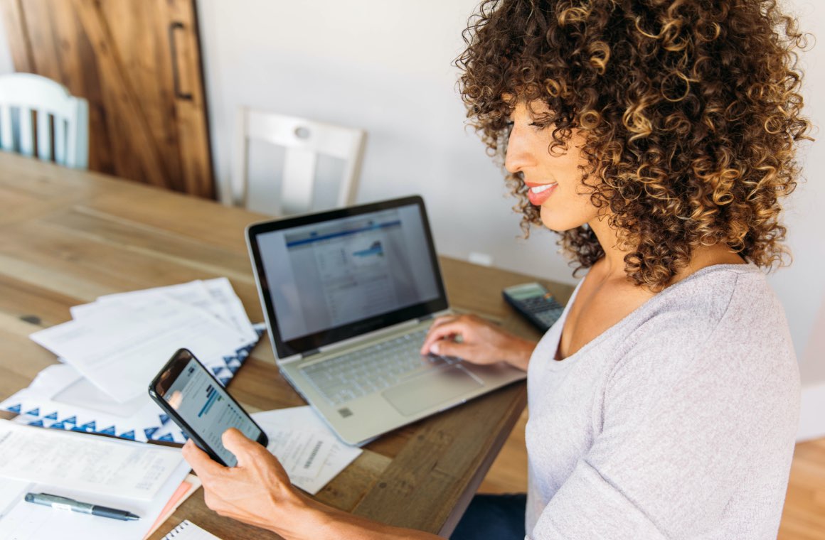 A woman working on a both mobile phone and laptop