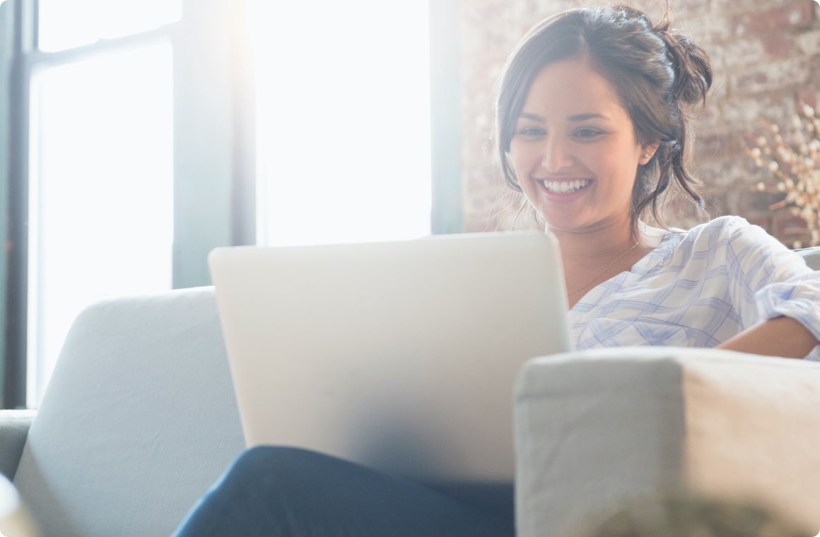 A woman on couch working on a laptop