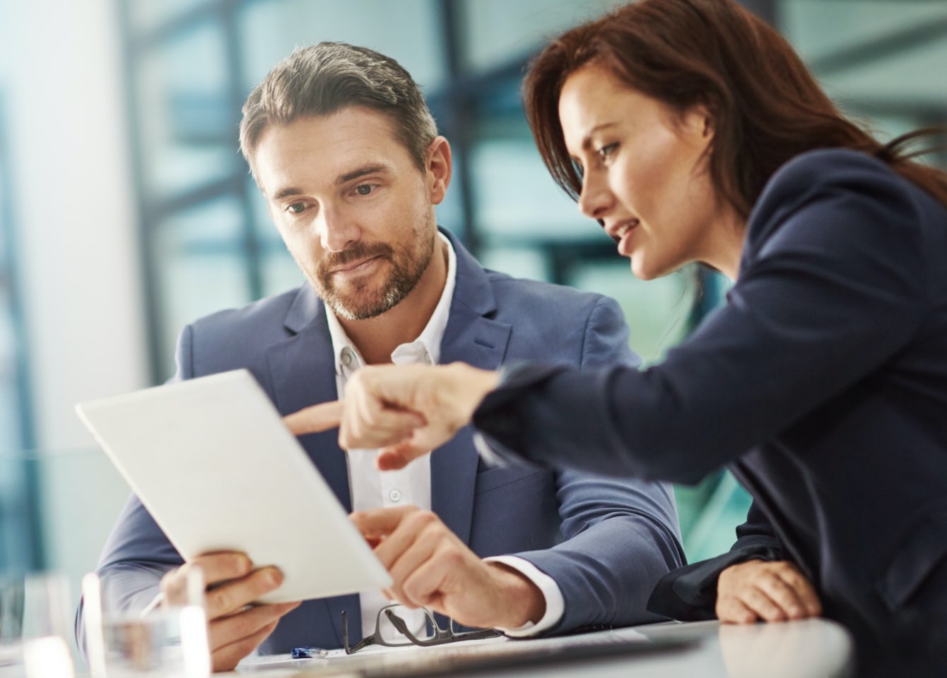 Two people looking at a tablet in a conference room