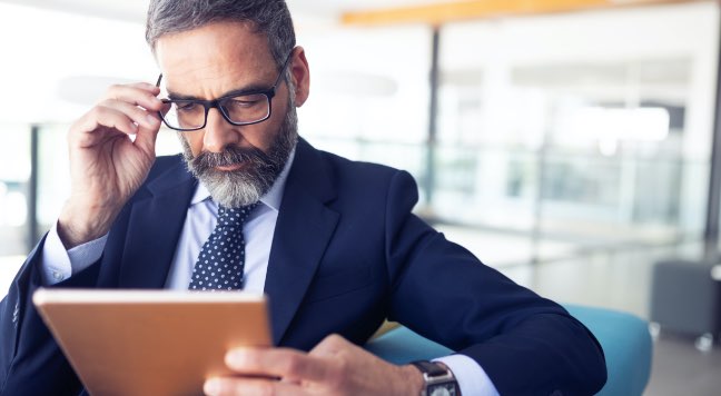 A man with glasses looking at a tablet