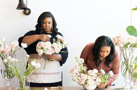 Two retail workers arranging flowers