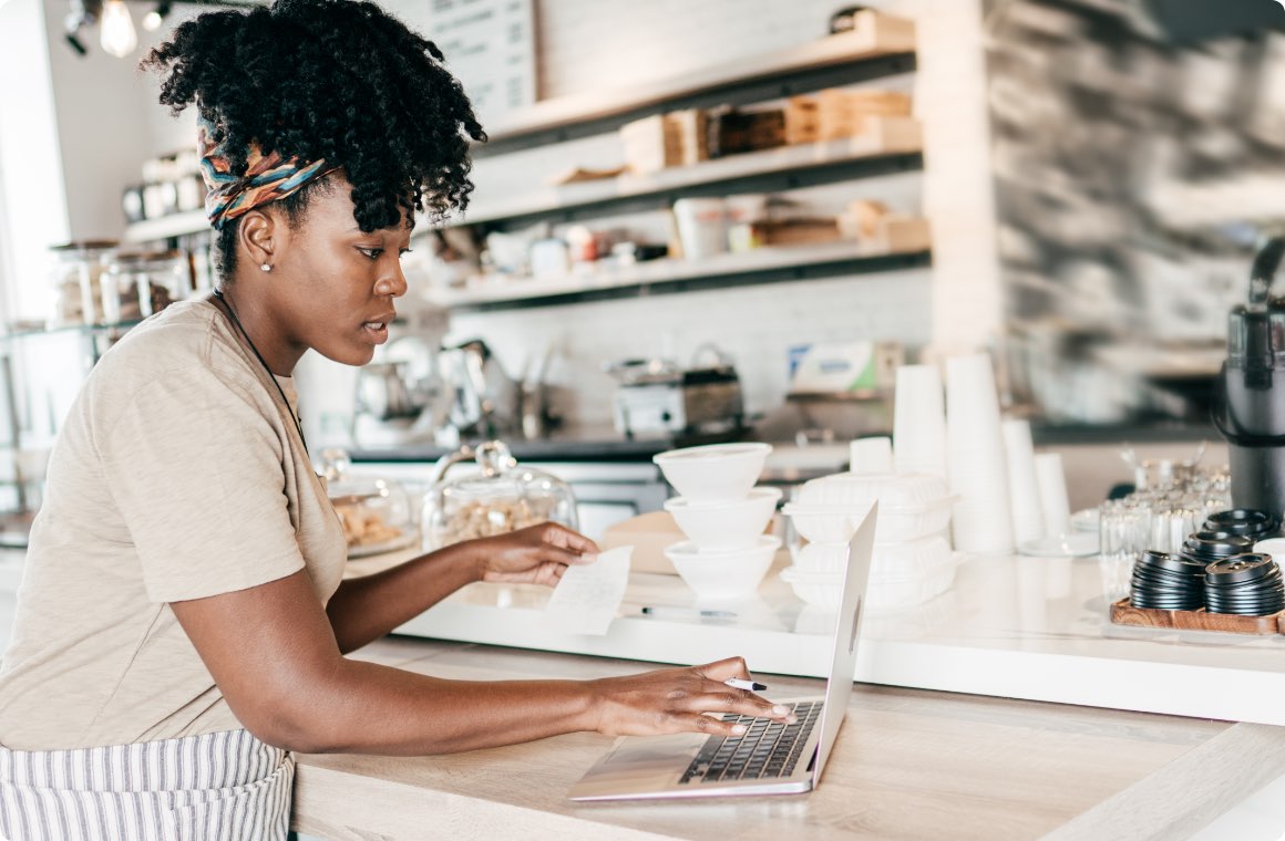 A woman managing a coffee shop business with a laptop