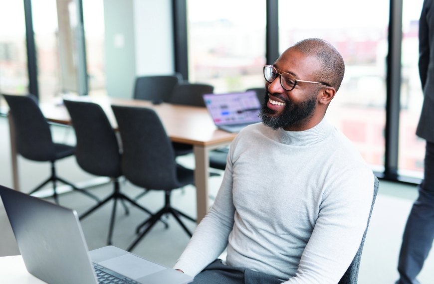 A Heartland employee sits in front of a laptop in a conference room, smiling.