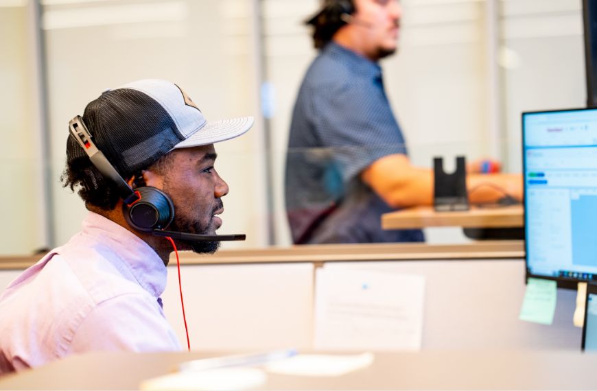 Male fintech sales employee wearing a headset and looking at a computer screen