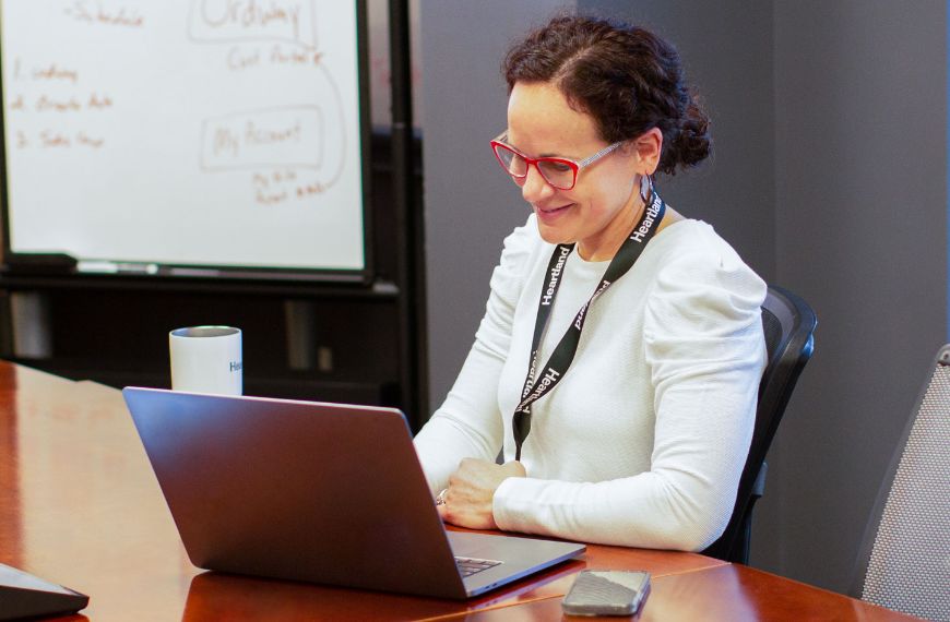 A female Heartland employee sits in front of a laptop computer in a conference room.