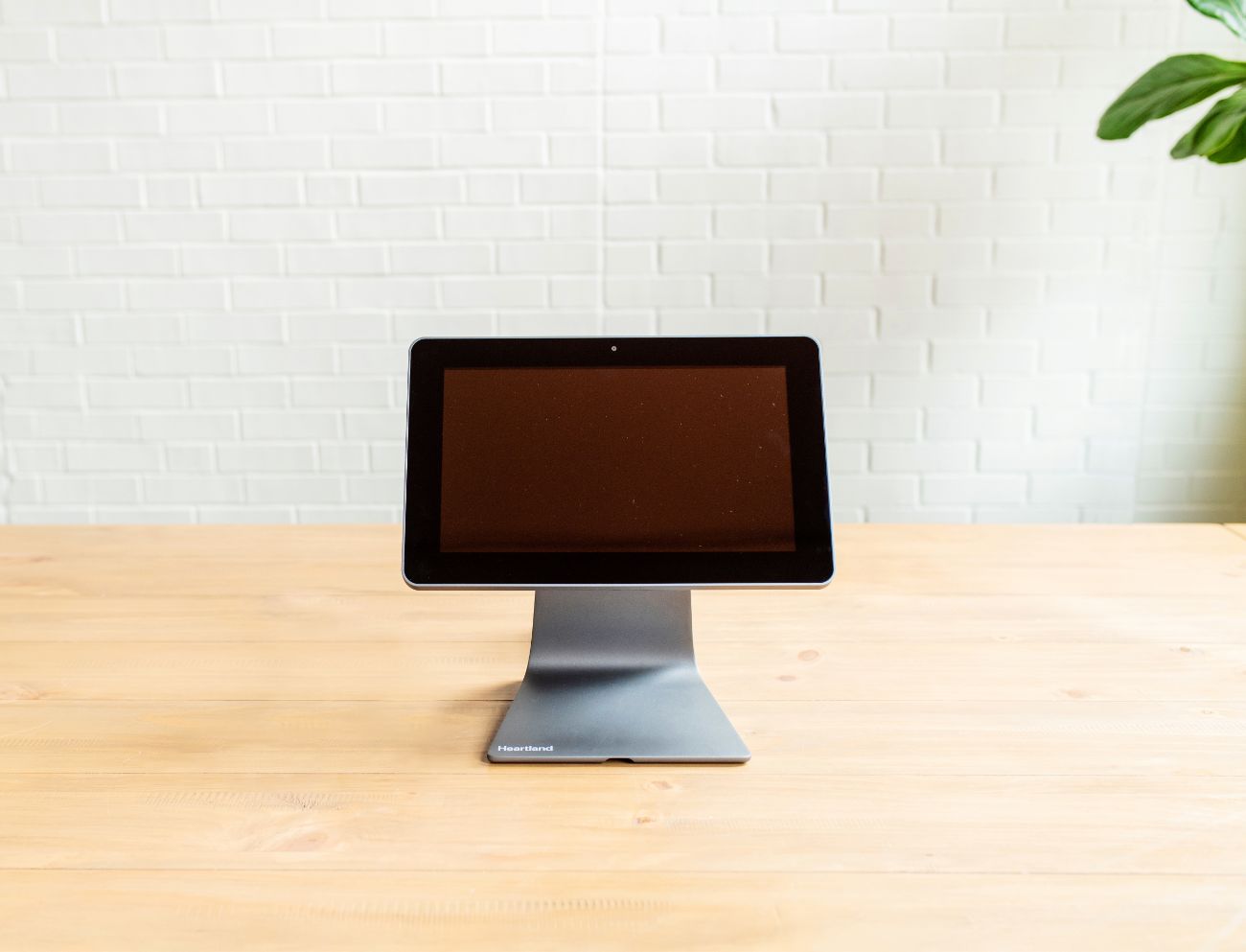A black screen POS device sitting on a wooden table.