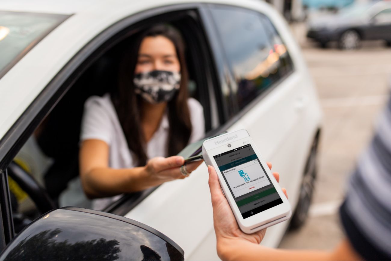 A woman paying with her phone from inside the car.