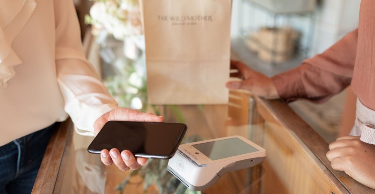 5 reasons to accept apple pay - person checking out using NFC and cell phone