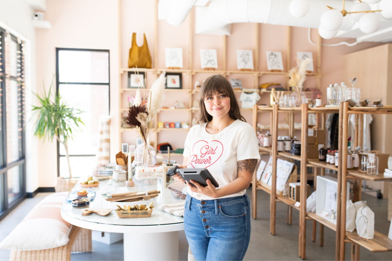 A female employee standing in the middle of a store a store with a tablet device. 