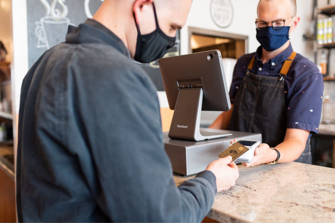 A credit card transaction between two people at a café type shop.