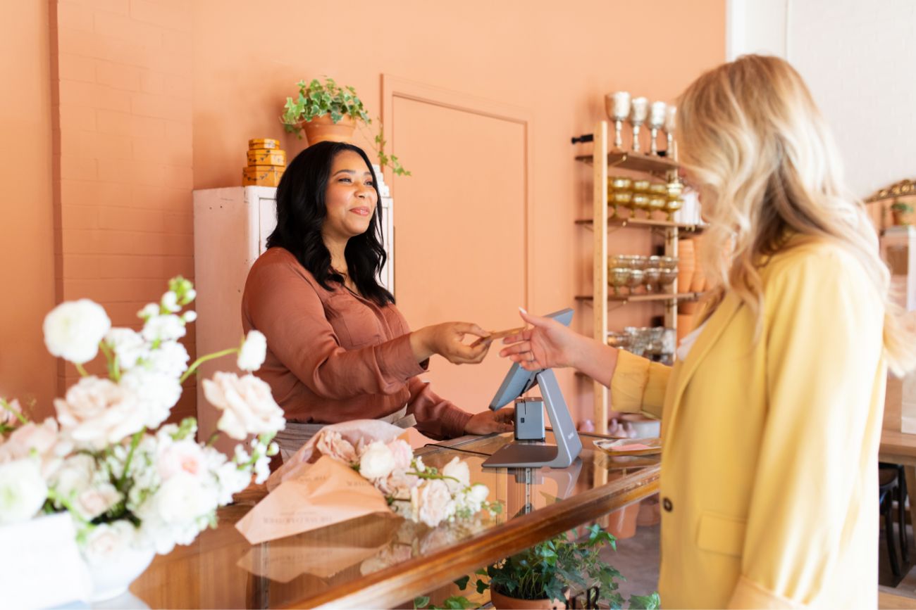 A woman handing a customer her credit card back.
