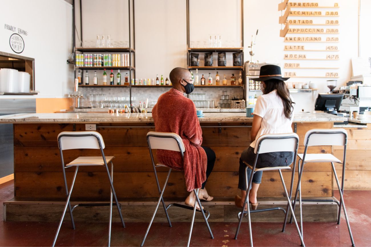 Two women sitting a bar top counter in a cafe. 