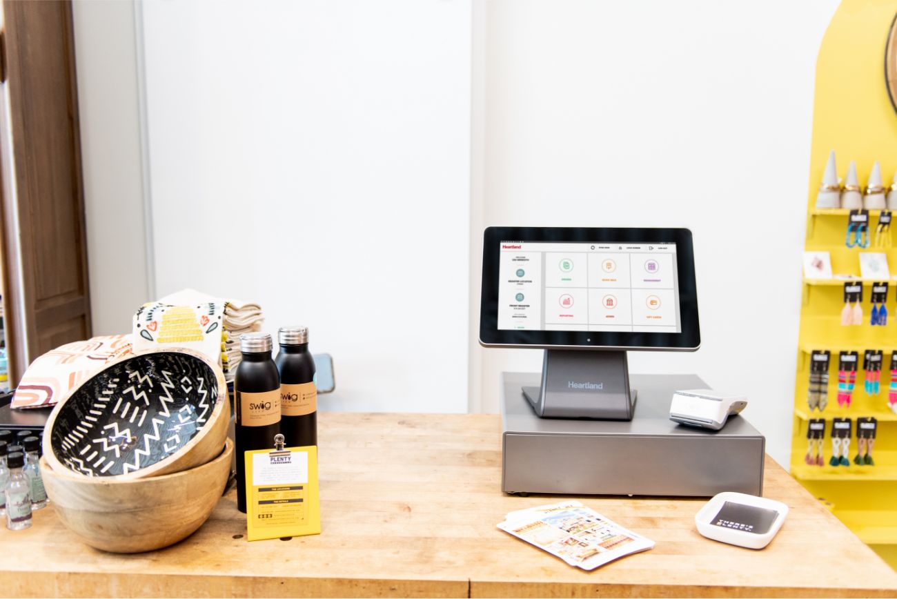 A POS system sitting on a table in a retail store with products sitting next to it on the table.