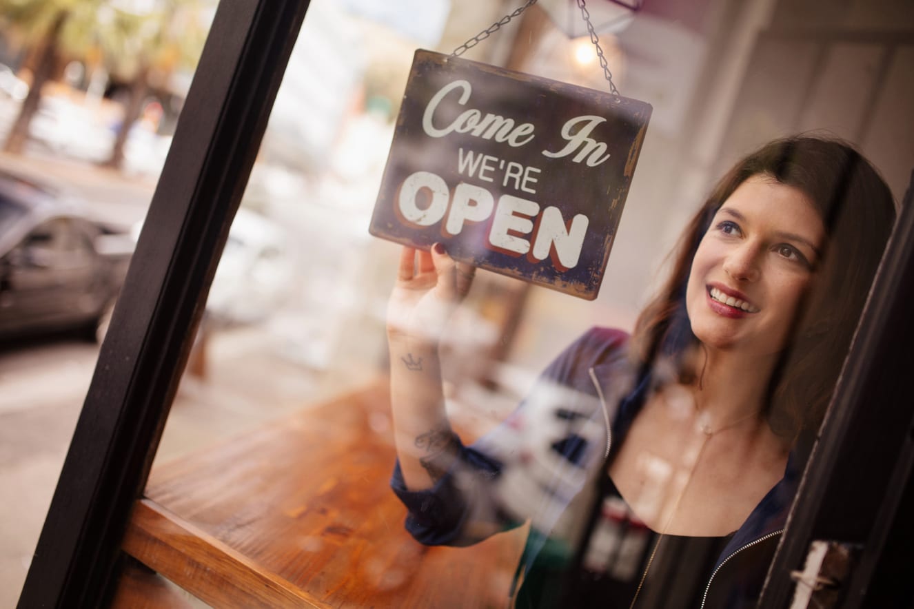 woman turning the sign of her business to open
