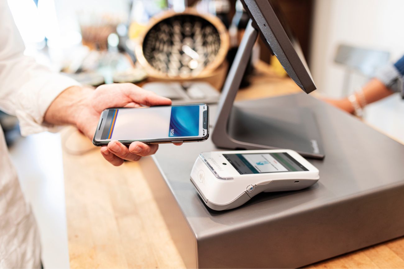 A hand holding a phone using mobile pay at a POS system on a table in a store.