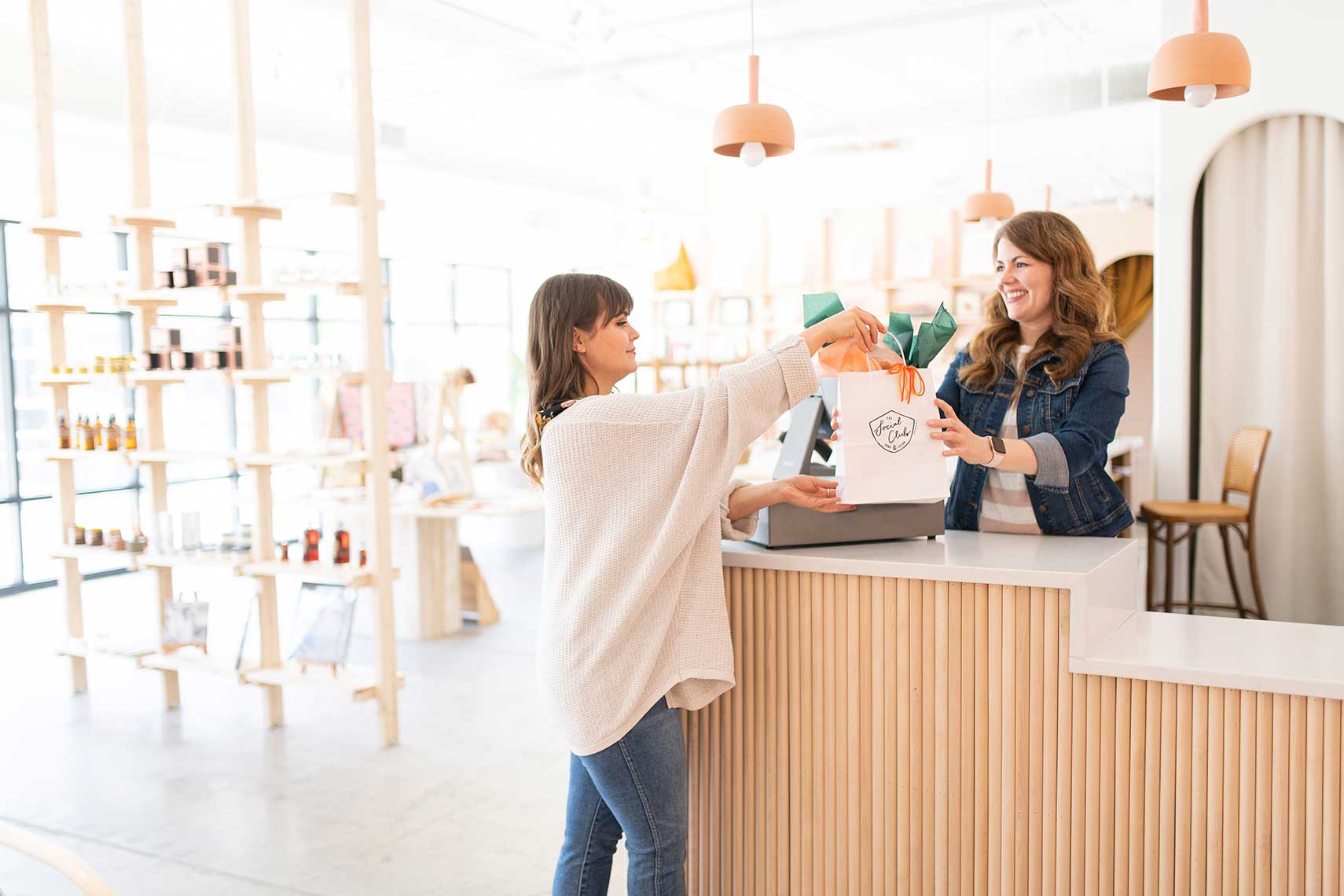 A woman buying something from another woman in a store.