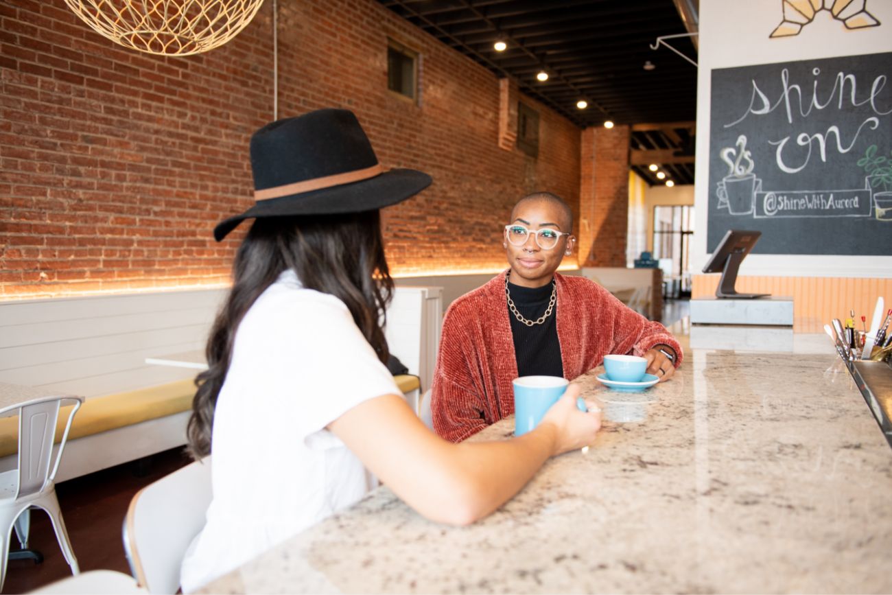 Two women with coffee cups sitting and talking 