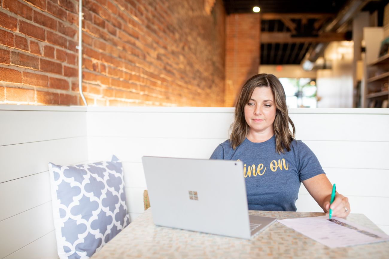 A female employee filling out paperwork at a computer.