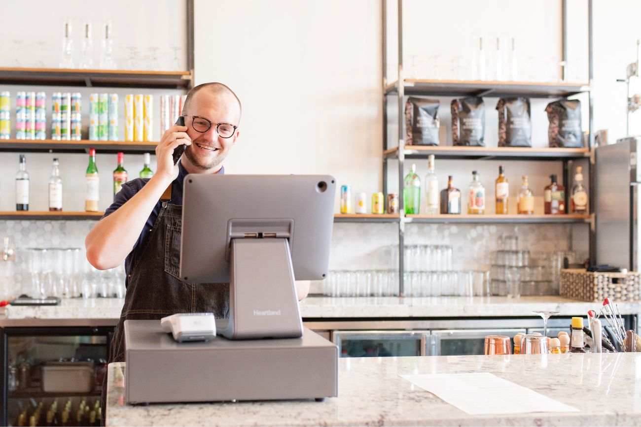 A man on the phone behind the counter with paperwork 