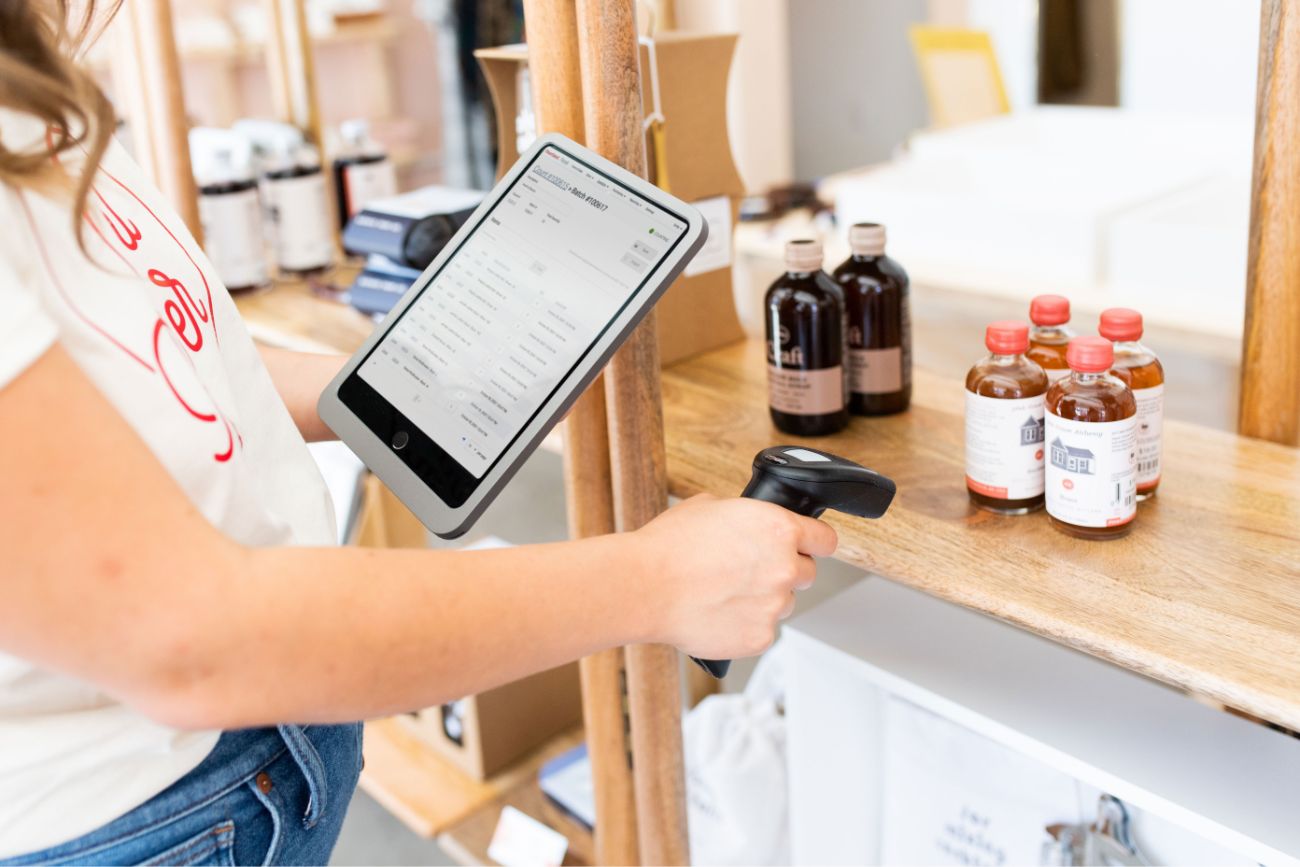 An employee scanning candles with a POS tablet and a scanner.