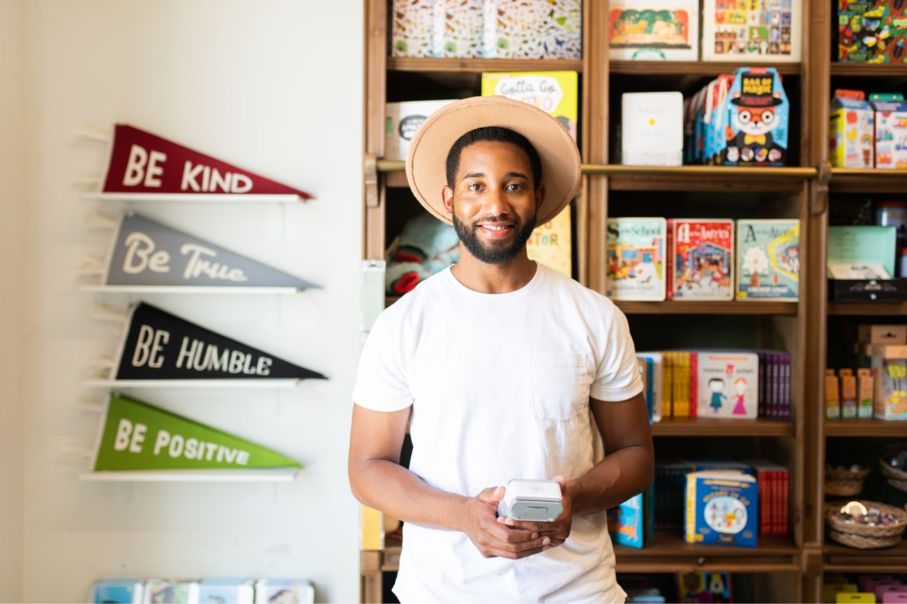 smiling employee holding a handheld payment device.