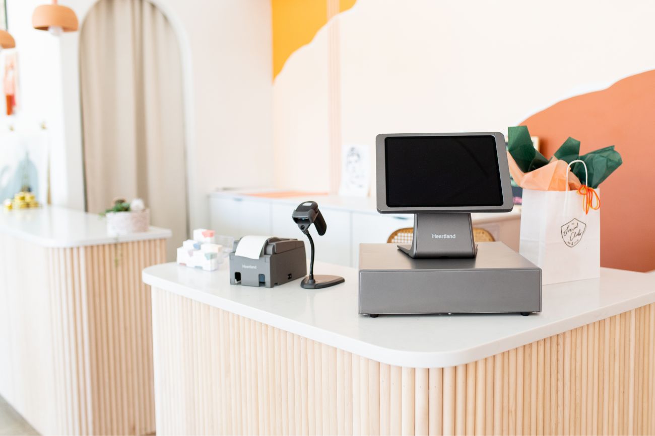 A POS system sitting on the counter of a retail store with a product scanner right next to it.