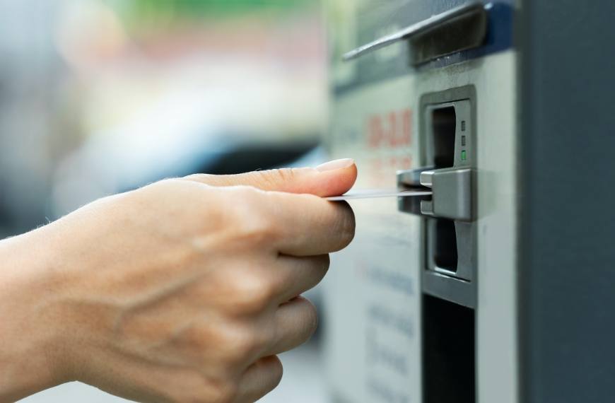 A closeup of a hand putting a card into a vending machine payment reader