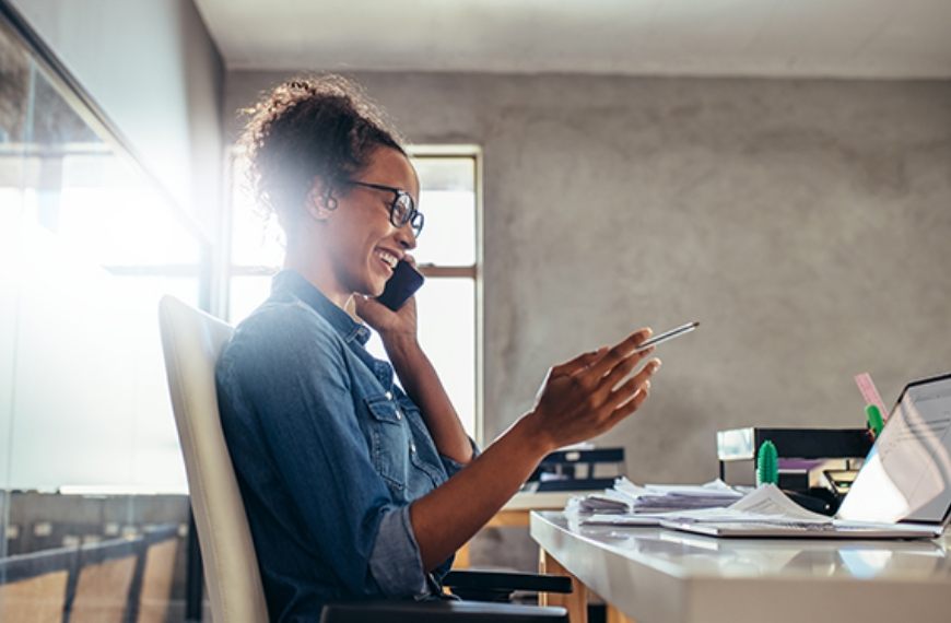 A woman speaking on her phone at a desk