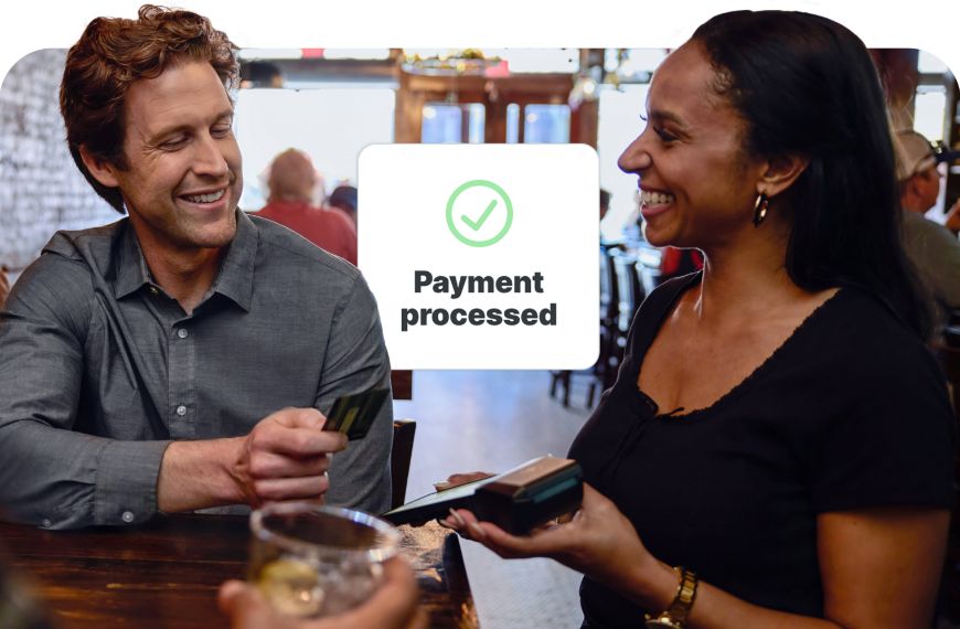 Man tapping his credit card on a handheld POS held by a woman at a restaurant