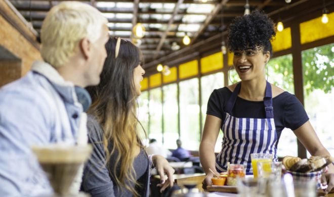 Female waitress delivering meals to a table of two in a restaurant