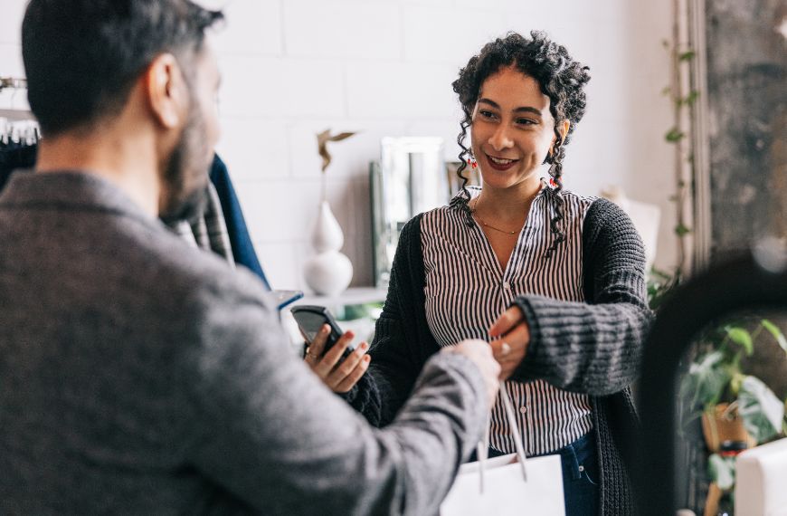 Store employee passing a shopping bag to a customer.