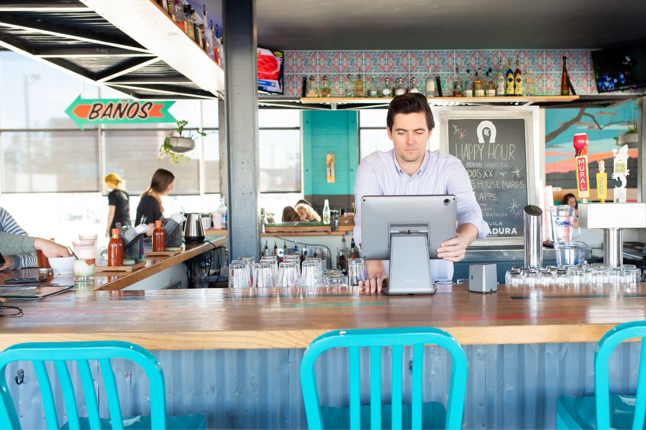 A man behind a restaurant counter using the POS system.