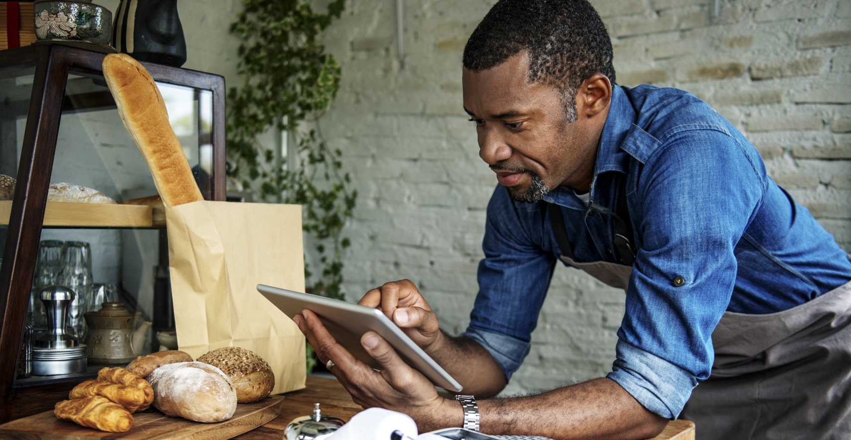 Small business person with an iPad looking over items and prices