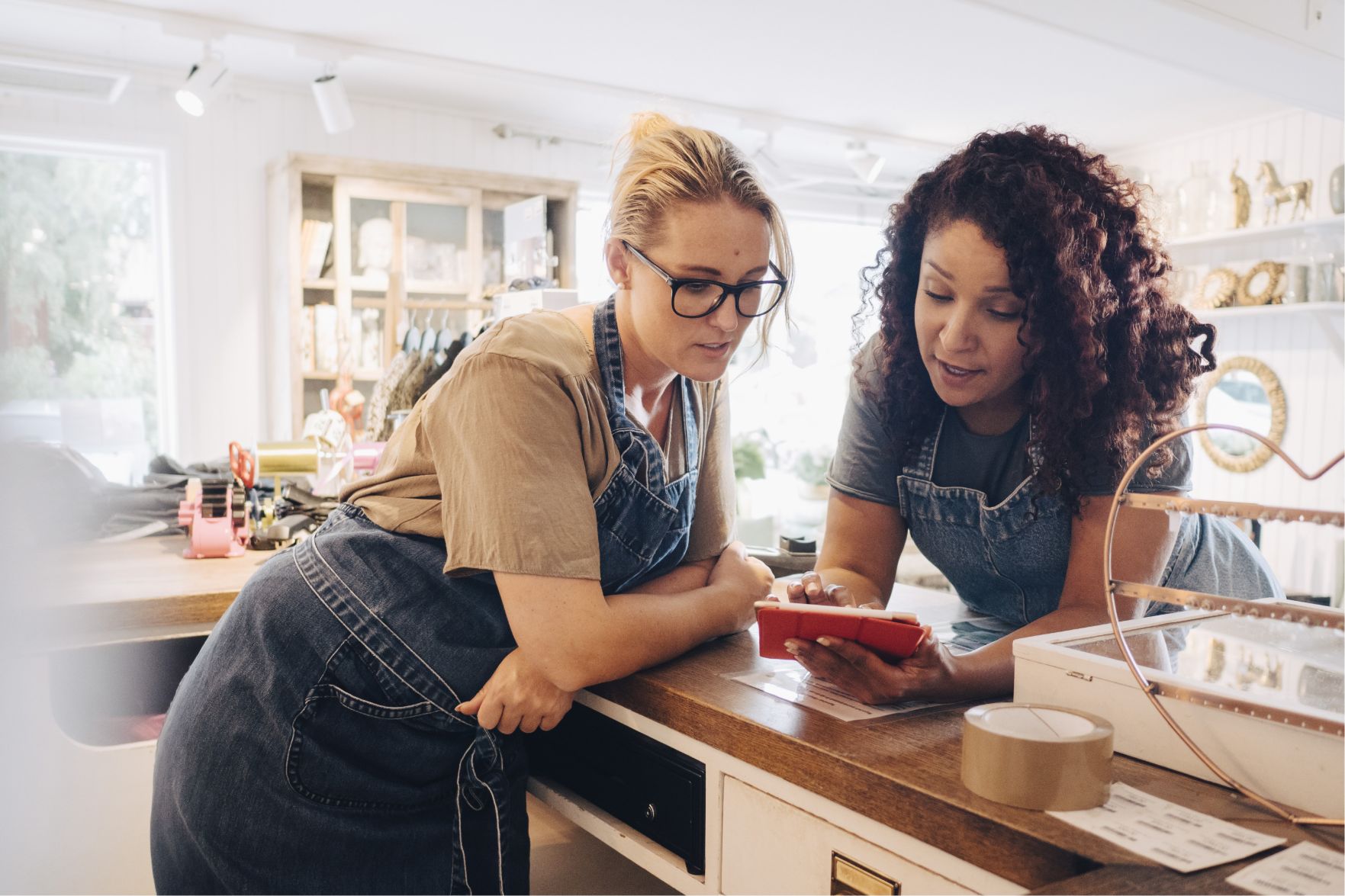 Two female employees looking at a mobile POS in a home goods store