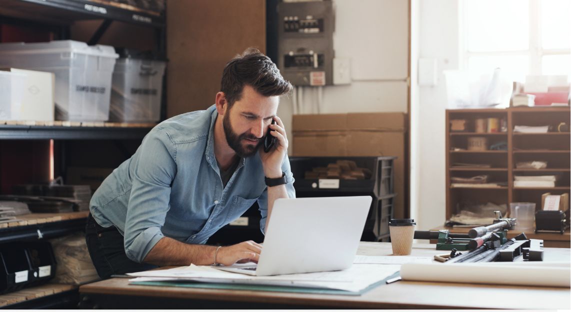 A man in a back office on phone hunched over a computer disputing a chargeback