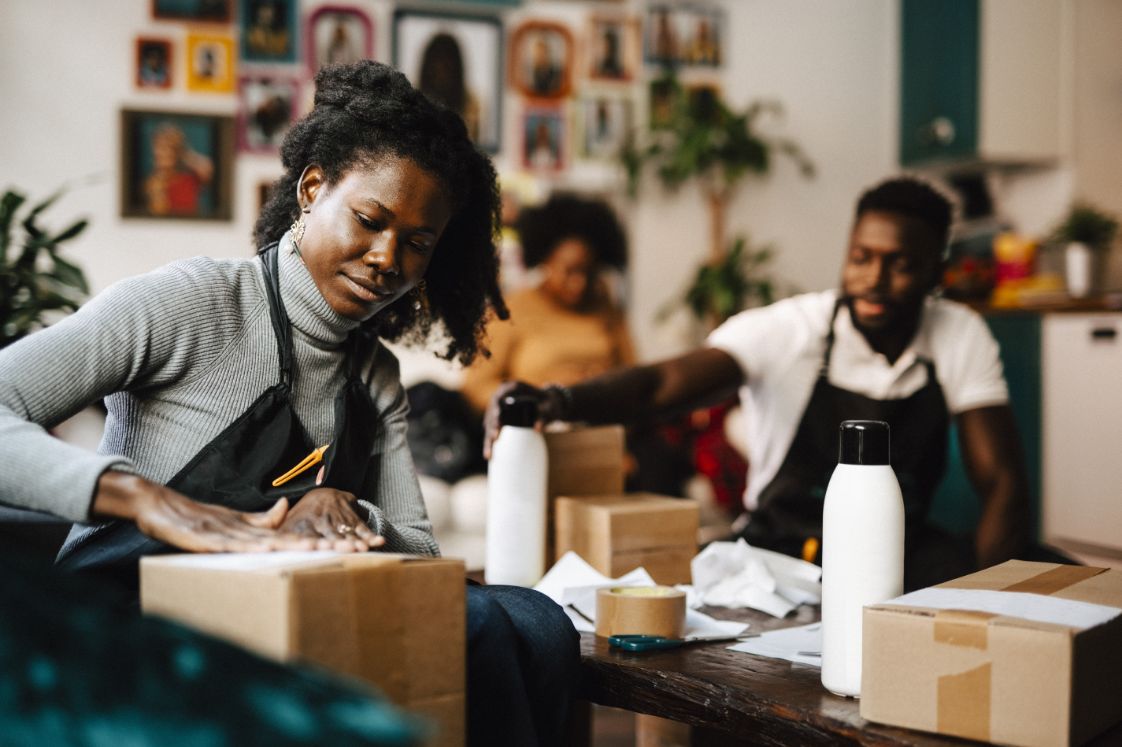 A male and female employee in a home goods store mailing online orders
