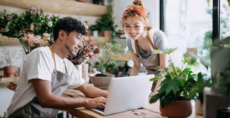 Manager and employee look at report on laptop