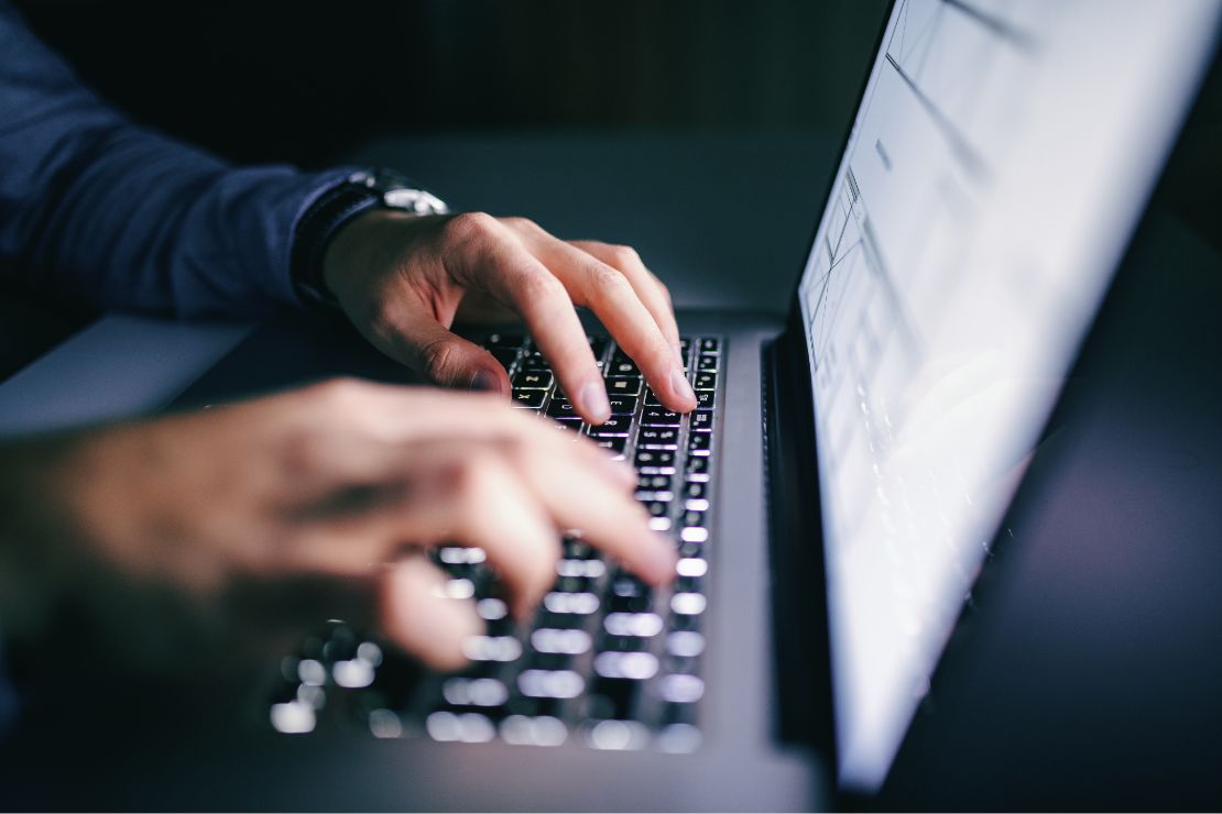 A close up photo of a person`s hands typing on a laptop computer.