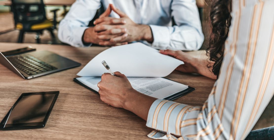 Two people sitting at desk go over paperwork for merchant services provider pricing structures.