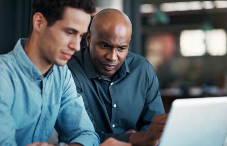Two males looking at an open laptop together