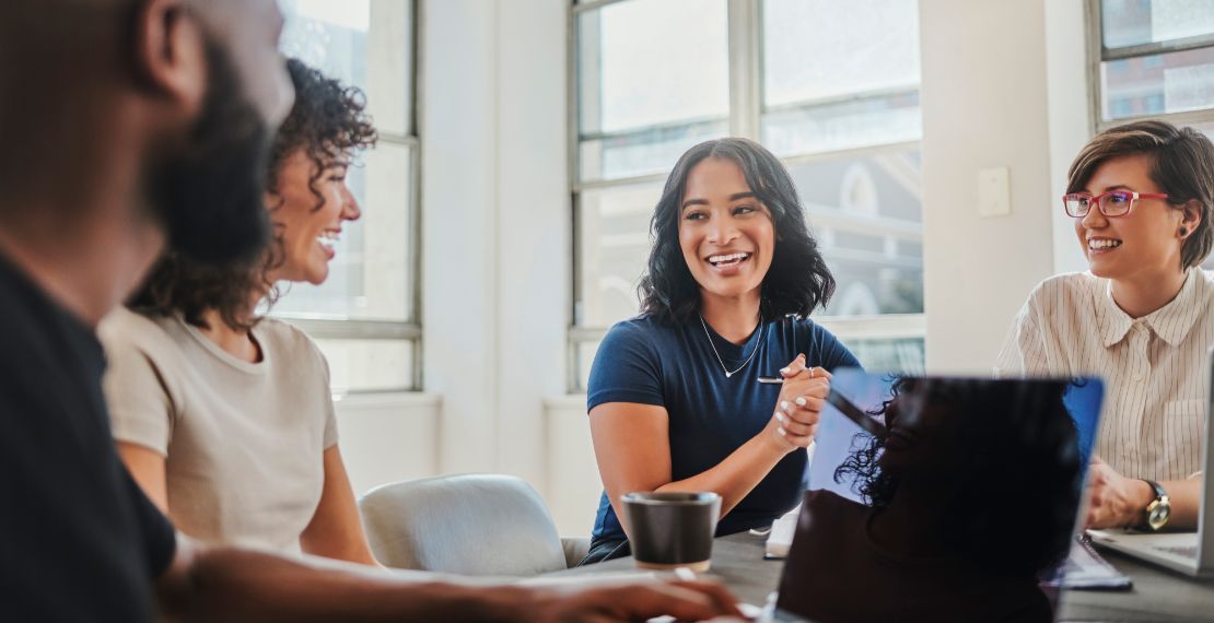 Four employees sitting around a laptop smiling while working on a brand collaboration 