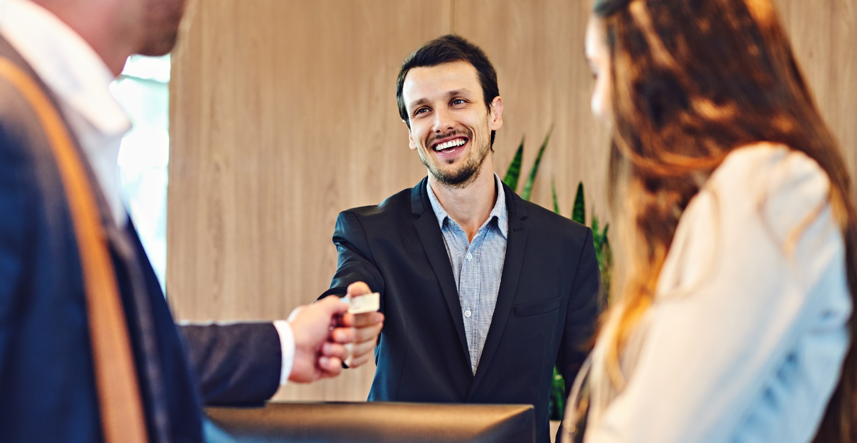 Hotel front desk associate looking over a hotel POS at two guests