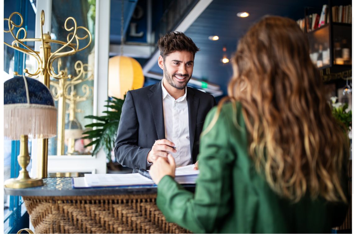 Male hotel front desk associate checking in a female guest