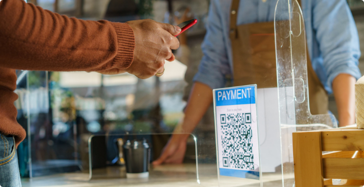 A closeup of a customer using their phone to scan a QR code to pay for coffee