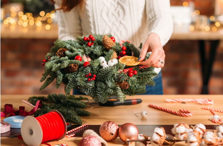 Close up of woman in cable knit sweater assembling a Christmas wreath