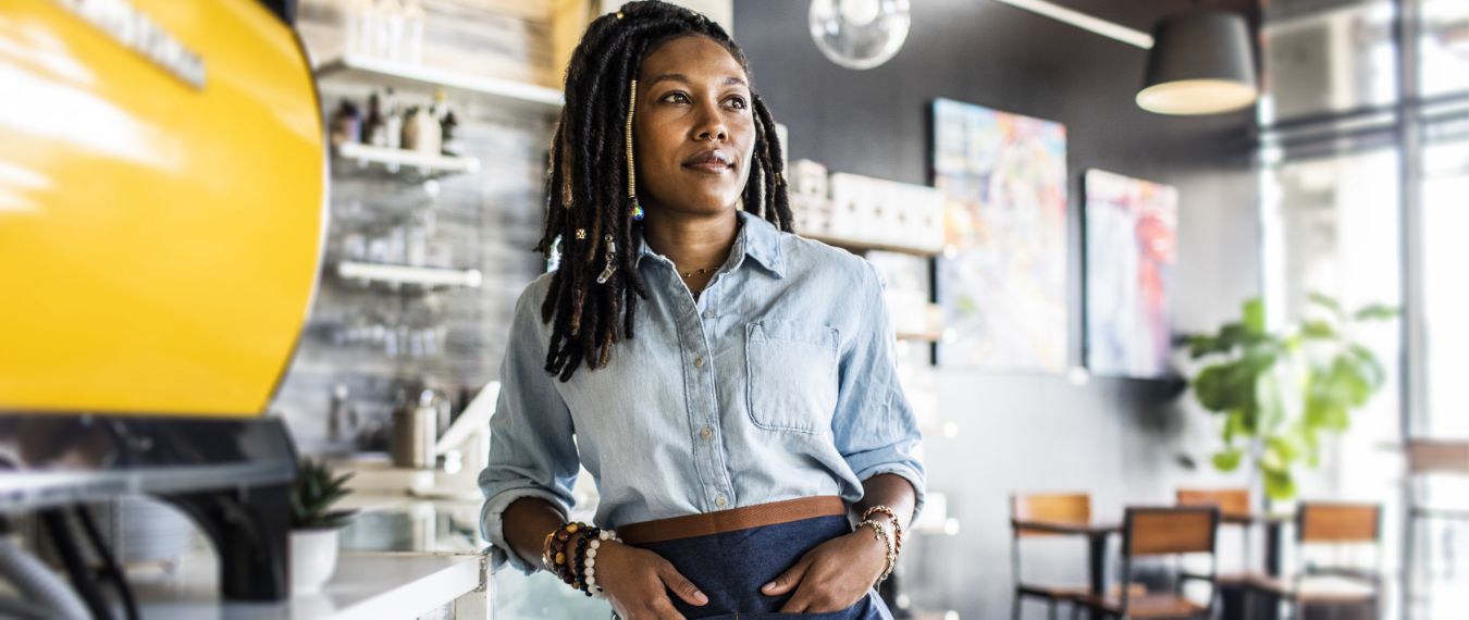 Woman standing in coffee shop thinks about her small business banking and lending options