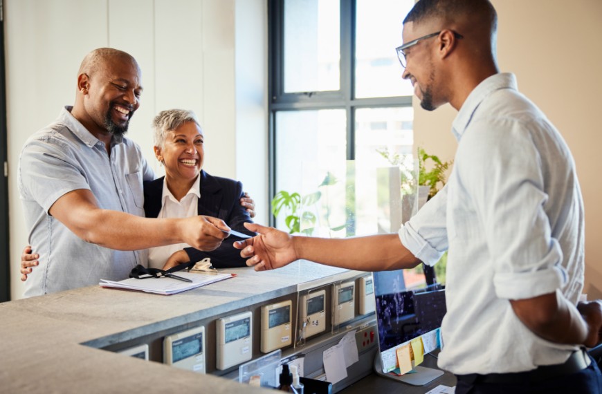 Hotel concierge accepts a credit card from a smiling couple ready to make a payment