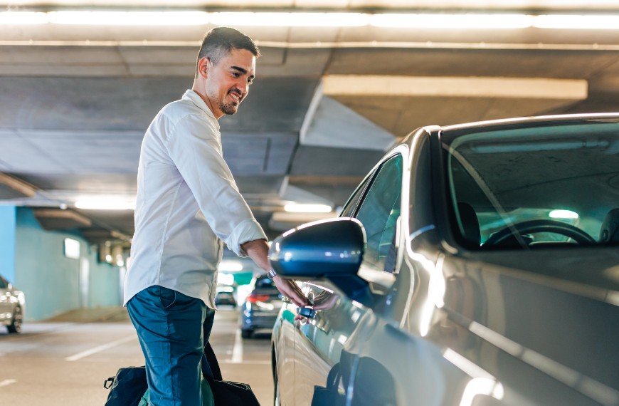 Man in parking garage opens his car door with a smile